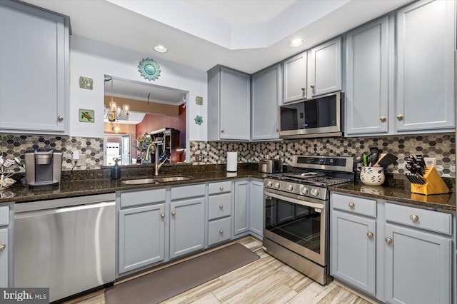 kitchen with appliances with stainless steel finishes, a sink, gray cabinets, decorative backsplash, and recessed lighting