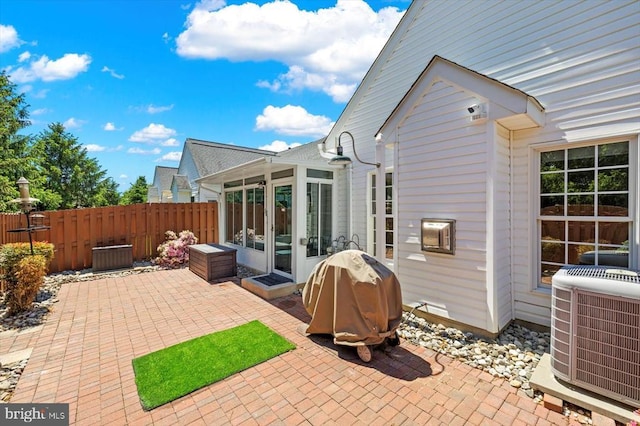 view of patio / terrace featuring a sunroom, central air condition unit, fence, and grilling area