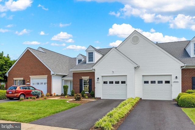 view of front of property with brick siding, a front yard, a shingled roof, and asphalt driveway