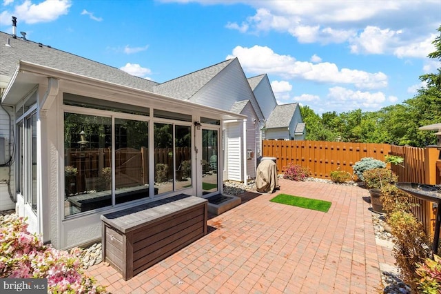 view of patio with fence and a sunroom