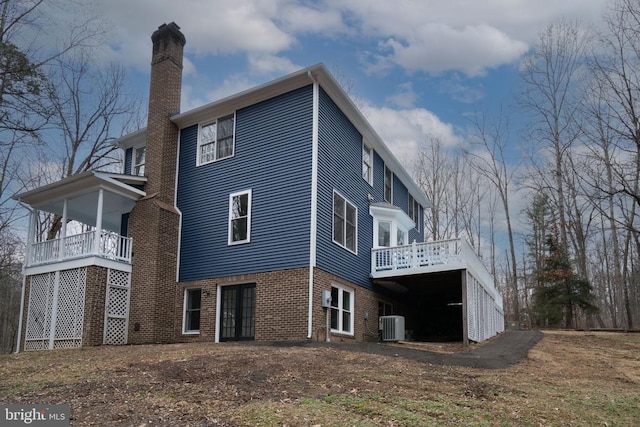 back of property with a chimney, central AC, a wooden deck, brick siding, and french doors