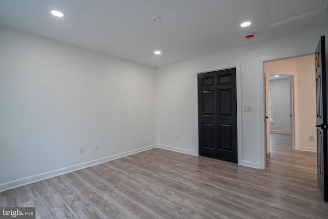 spare room with wood finished floors, baseboards, and recessed lighting