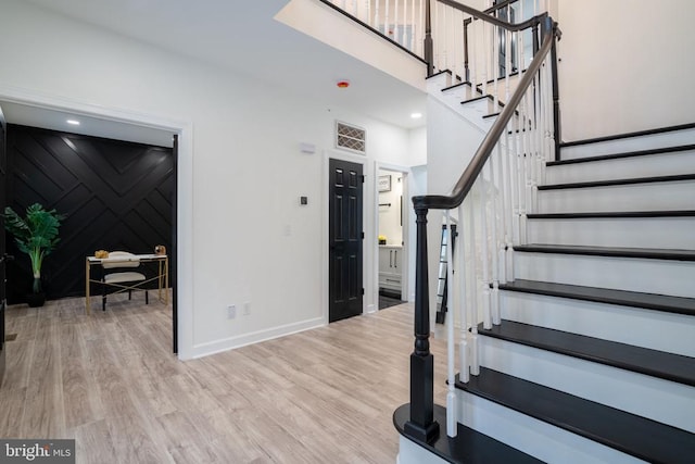 stairway featuring wood finished floors, baseboards, and a high ceiling