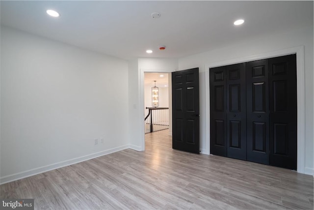 unfurnished bedroom featuring a chandelier, light wood-type flooring, a closet, baseboards, and recessed lighting