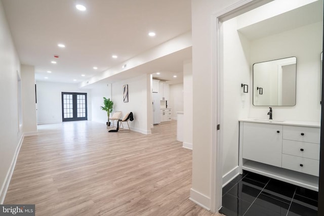 hall with a sink, light wood-style flooring, baseboards, and recessed lighting