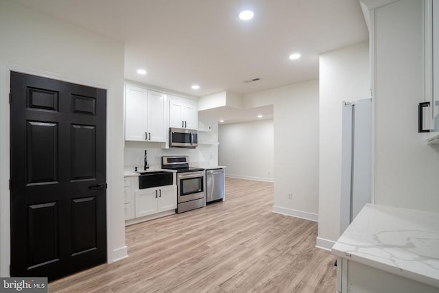 kitchen with stainless steel appliances, white cabinetry, light wood-style flooring, baseboards, and open shelves
