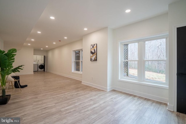unfurnished room with washing machine and clothes dryer, light wood-style flooring, recessed lighting, and baseboards