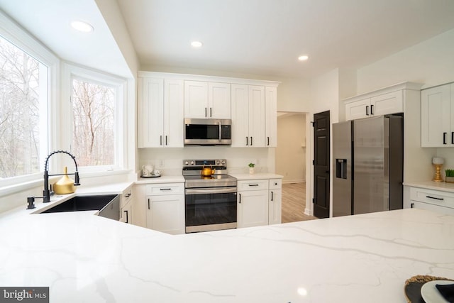 kitchen featuring stainless steel appliances, a sink, white cabinetry, and recessed lighting