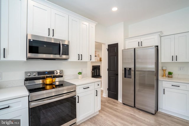 kitchen featuring stainless steel appliances, white cabinets, light countertops, light wood-type flooring, and recessed lighting