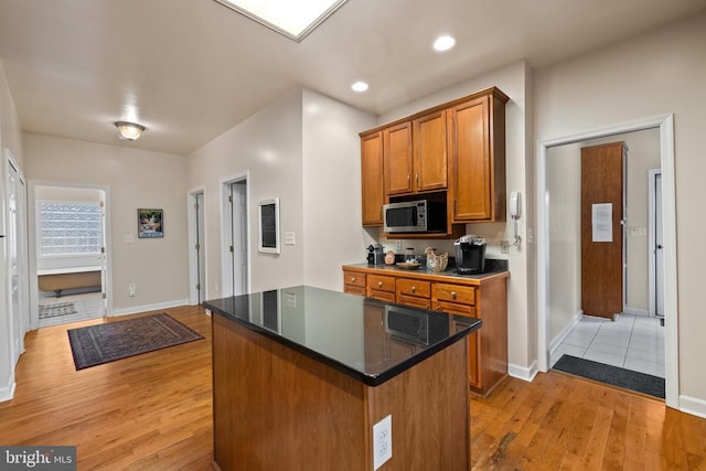 6005 Page Valley Rd, Luray, VA 22835 - kitchen featuring stainless steel microwave, light wood-type flooring, brown cabinetry, a kitchen island, and baseboards