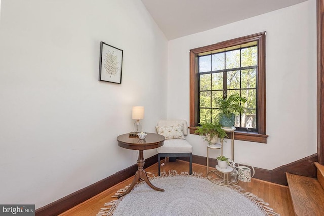 sitting room with wood finished floors, lofted ceiling, baseboards, and stairway