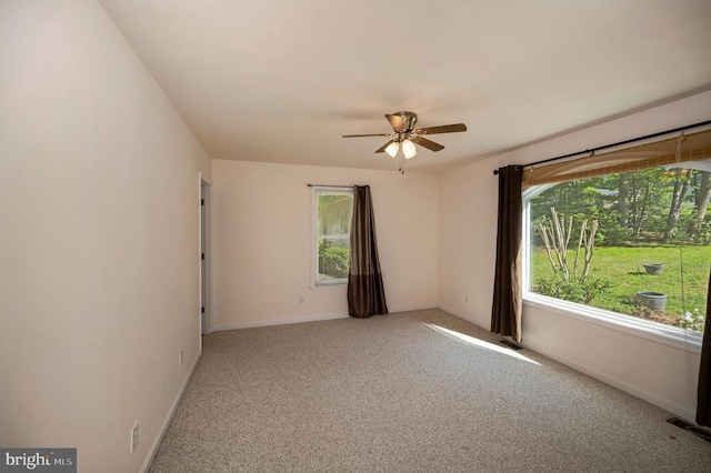 unfurnished room featuring plenty of natural light, ceiling fan, light carpet, and baseboards