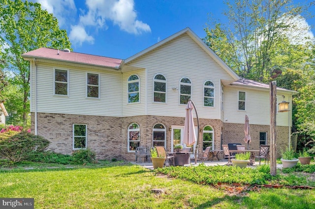 rear view of property featuring brick siding, a patio, and a lawn