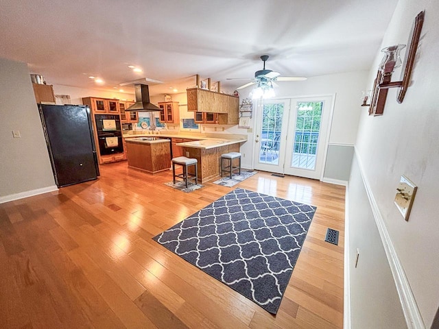 209 Raintree Rd, Verona, VA 24482 - kitchen featuring island exhaust hood, black appliances, brown cabinetry, light wood-style flooring, and a ceiling fan