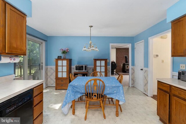 13403 Motts Run Rd, Fredericksburg, VA 22407 - dining space featuring a wood stove, light floors, a chandelier, and a wainscoted wall