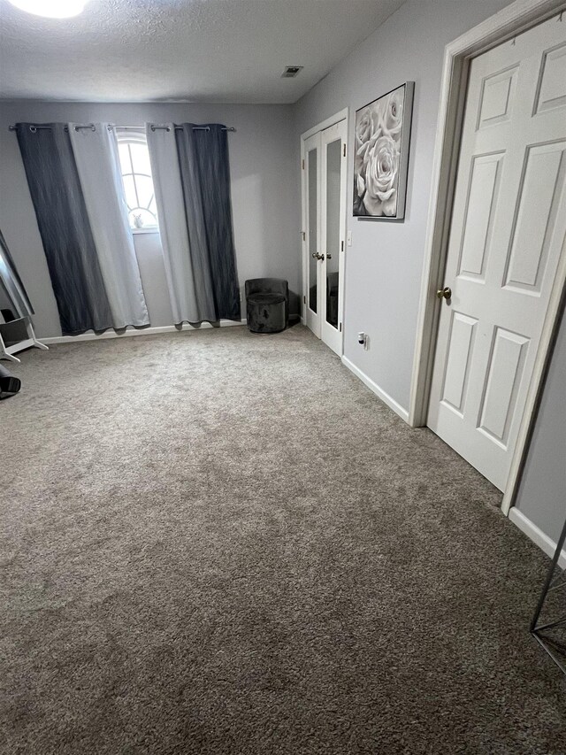 carpeted spare room with baseboards, french doors, visible vents, and a textured ceiling