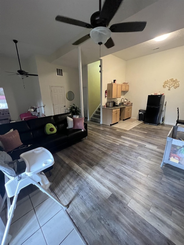 living area featuring stairs, visible vents, ceiling fan, and wood finished floors