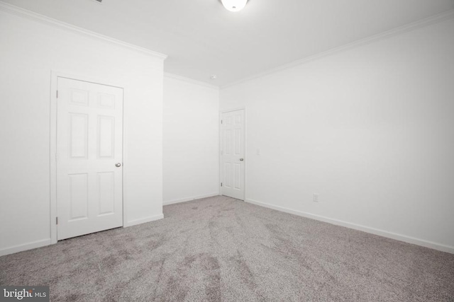 empty room with ornamental molding, carpet flooring, and baseboards
