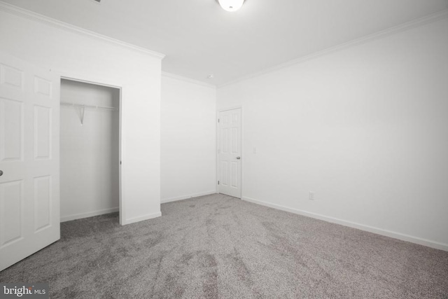 unfurnished bedroom with ornamental molding, carpet flooring, a closet, and baseboards