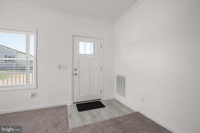 entrance foyer featuring crown molding, baseboards, and carpet