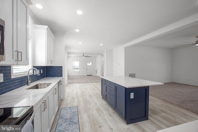 kitchen featuring open floor plan, ceiling fan, a sink, white cabinetry, and blue cabinetry