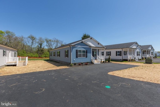 manufactured / mobile home featuring asphalt driveway, covered porch, and central AC unit