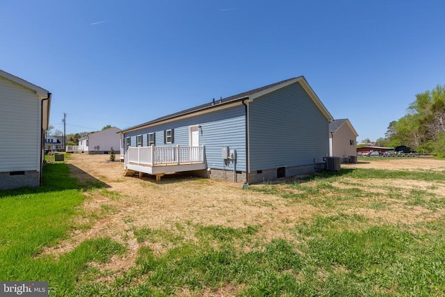 rear view of property featuring crawl space, central AC, a wooden deck, and a lawn