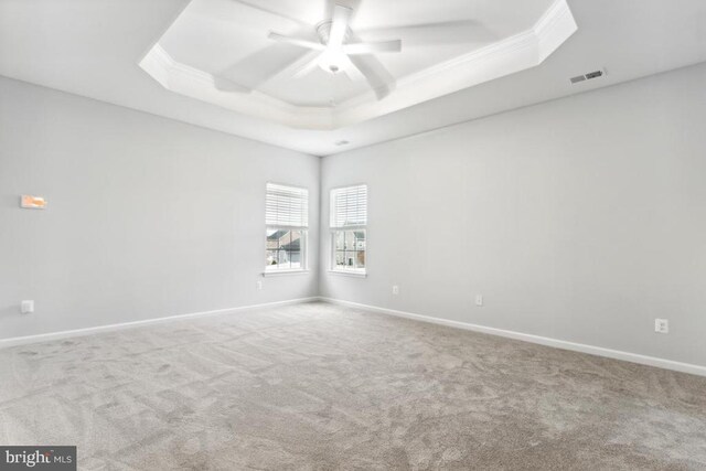 carpeted spare room featuring crown molding, a ceiling fan, baseboards, and a tray ceiling