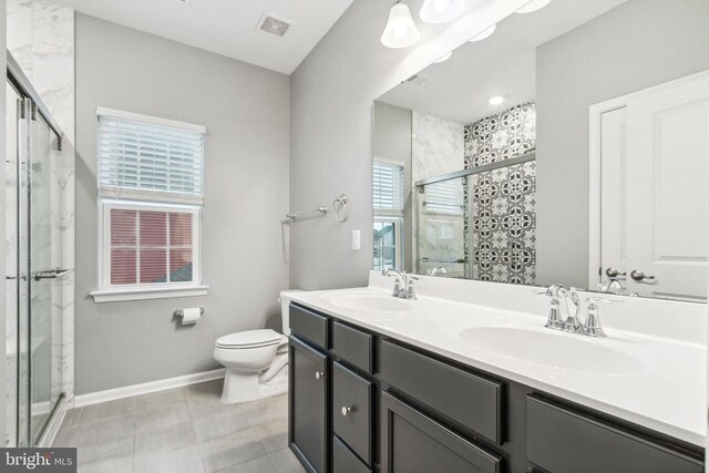full bath featuring a shower stall, toilet, double vanity, and baseboards