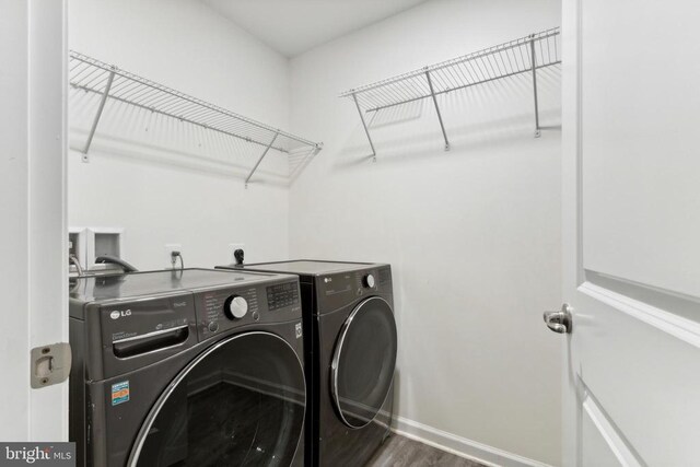 laundry area featuring washer and dryer, baseboards, and wood finished floors