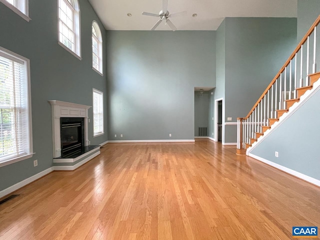 1142 Redfields Rd, Charlottesville, VA 22903 - unfurnished living room featuring a towering ceiling, light wood-style floors, ceiling fan, plenty of natural light, and stairs