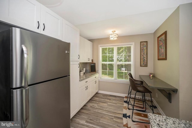 10118 New Scotland Dr, Fredericksburg, VA 22408 - kitchen featuring freestanding refrigerator, wood finished floors, white cabinetry, baseboards, and light stone counters