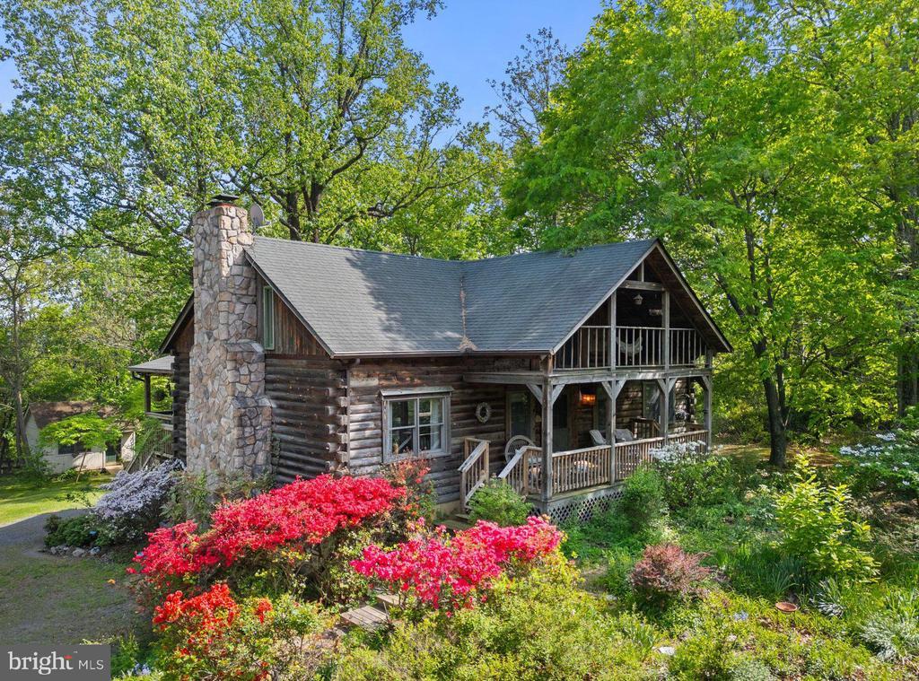  - log home featuring a chimney, a porch, a shingled roof, and log exterior