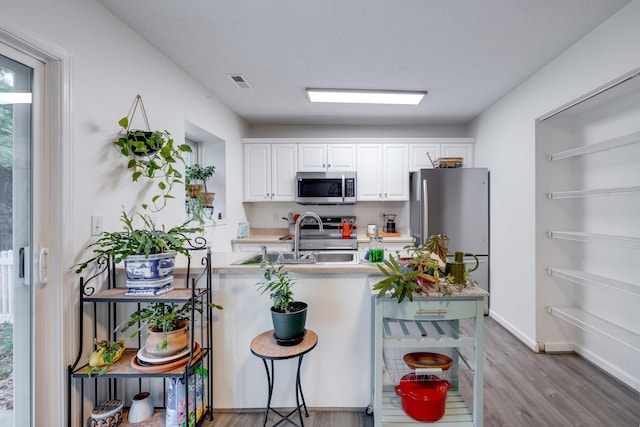 1045 Alexander Hamilton Ln, Harrisonburg, VA 22802 - kitchen with appliances with stainless steel finishes, wood finished floors, light countertops, white cabinetry, and a sink