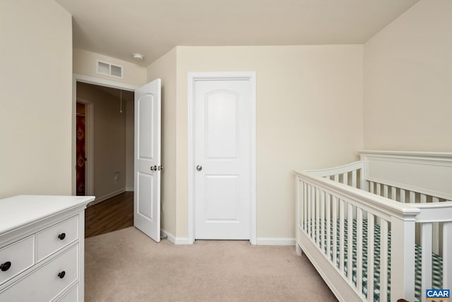 bedroom featuring light colored carpet, a crib, visible vents, and baseboards