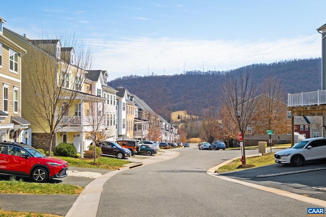 view of street featuring traffic signs, street lights, a mountain view, and a residential view