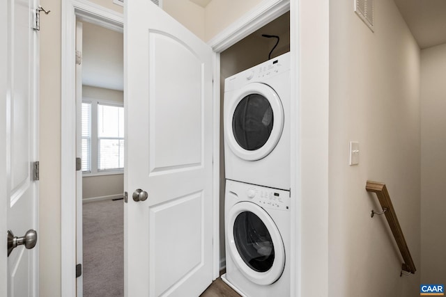 clothes washing area with baseboards, carpet flooring, visible vents, stacked washer and clothes dryer, and laundry area