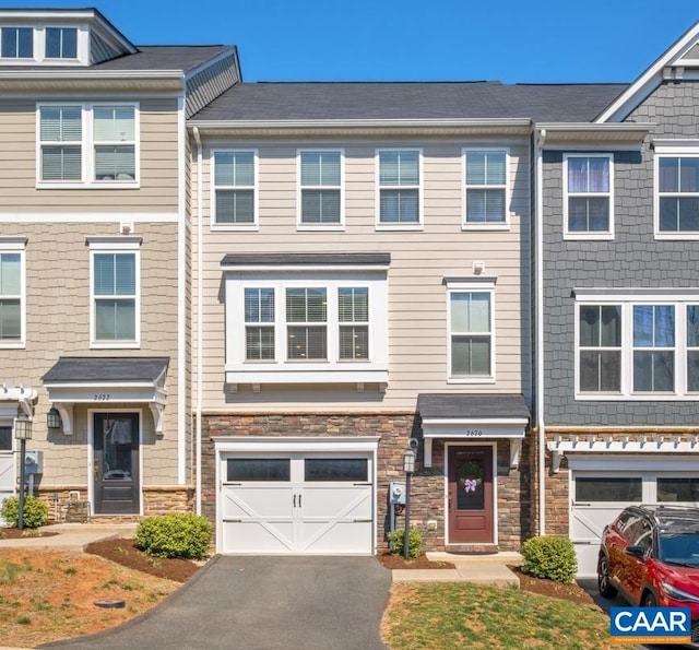 multi unit property featuring stone siding, aphalt driveway, and an attached garage