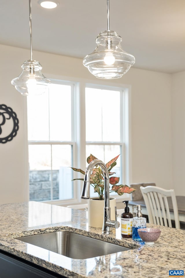 room details with light stone countertops, a sink, and decorative light fixtures