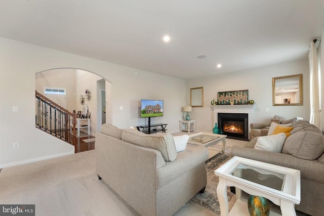 12804 Monterey Ct, Fredericksburg, VA 22407 - living room featuring arched walkways, a glass covered fireplace, stairs, light carpet, and recessed lighting