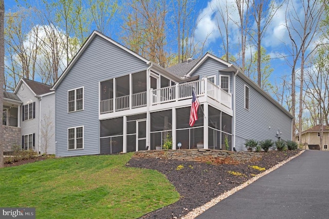 back of house with a sunroom and a lawn