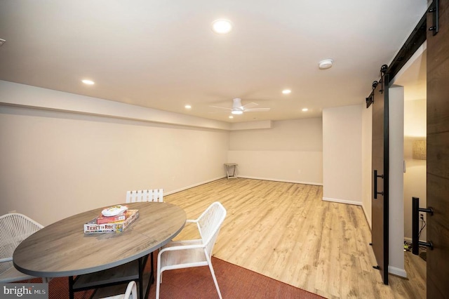 dining area featuring a barn door, light wood-type flooring, a ceiling fan, recessed lighting, and baseboards
