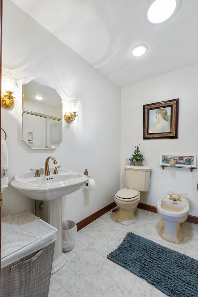 bathroom featuring toilet, baseboards, and a bidet
