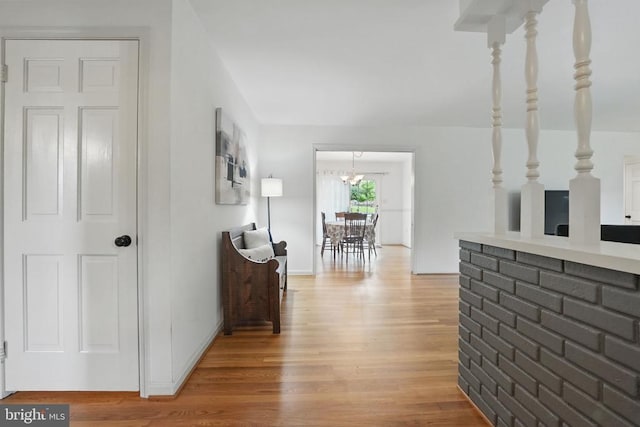  - hallway featuring light wood finished floors, a chandelier, and baseboards