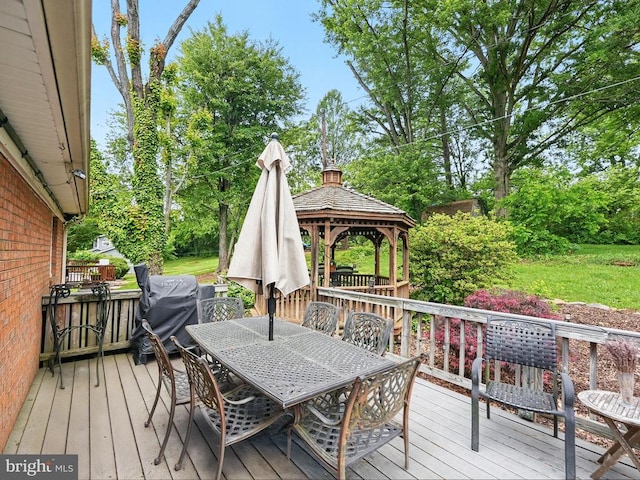  - deck with outdoor dining area, a gazebo, and view of wooded area