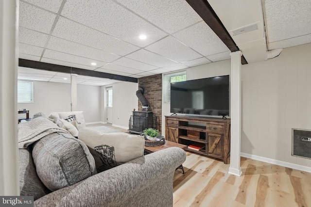  - living area with a wood stove, wood finished floors, baseboards, a drop ceiling, and recessed lighting