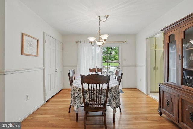  - dining area with a chandelier, light wood finished floors, and baseboards