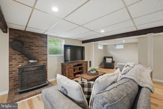 - living area with a wood stove, wood finished floors, baseboards, a paneled ceiling, and recessed lighting