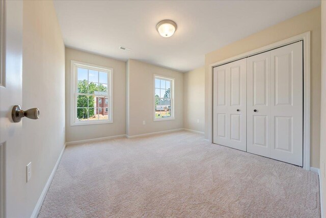 unfurnished bedroom with carpet, baseboards, and a closet