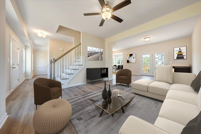 living room with wood finished floors, stairs, ceiling fan, and baseboards